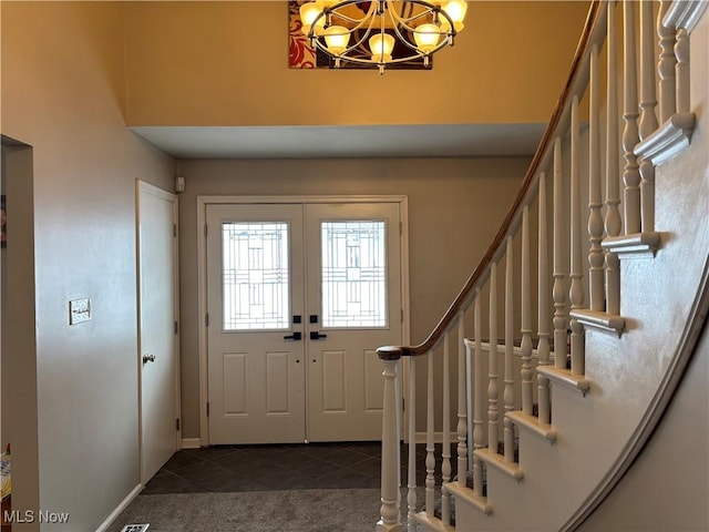 entrance foyer with a notable chandelier, dark tile patterned floors, baseboards, stairs, and dark colored carpet