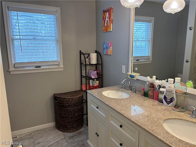 full bath with double vanity, baseboards, toilet, and a sink