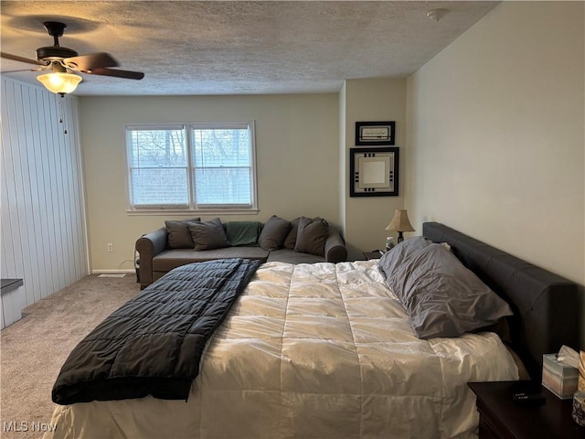 bedroom with a textured ceiling, carpet floors, and ceiling fan