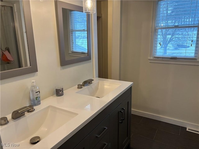 full bath with double vanity, a sink, visible vents, and baseboards