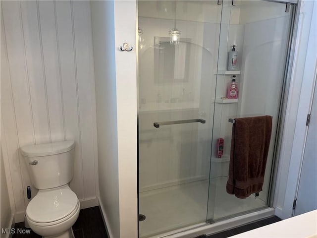 bathroom featuring toilet and a shower stall