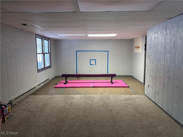 below grade area with carpet floors, baseboard heating, and a paneled ceiling