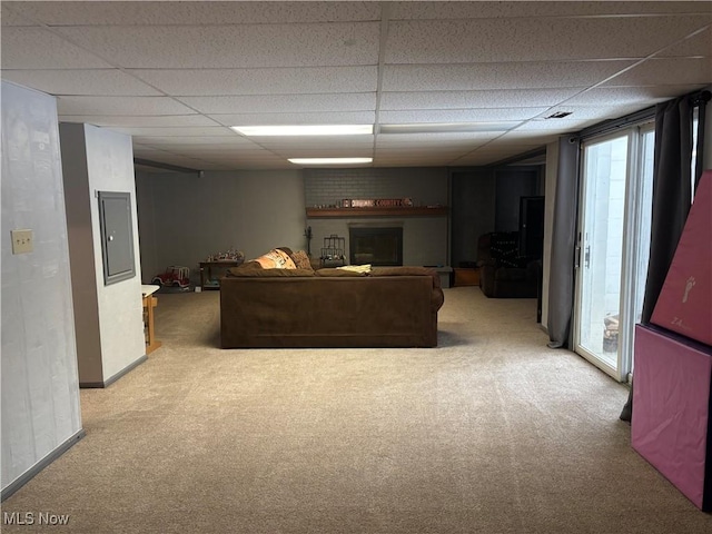 living area featuring baseboards, a drop ceiling, and light colored carpet