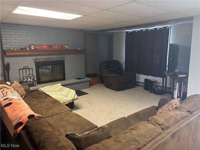 carpeted living room with a brick fireplace and a drop ceiling