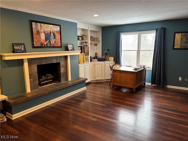 office featuring a fireplace, baseboards, dark wood finished floors, and built in features