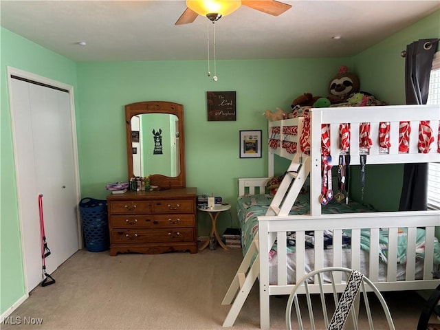 bedroom with a ceiling fan, a closet, and light carpet