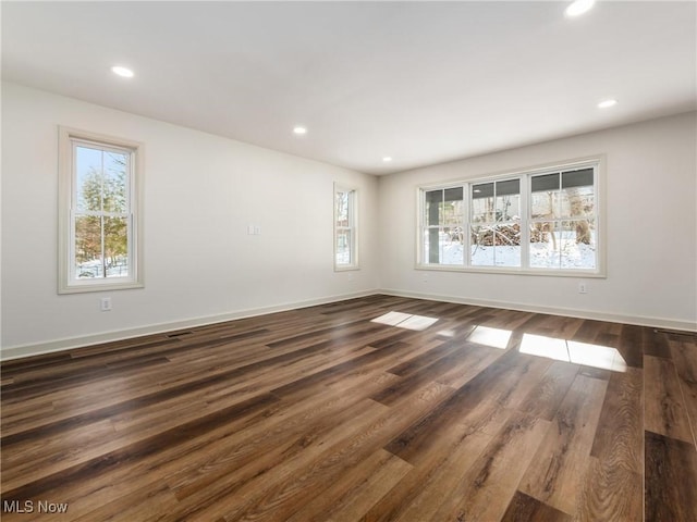 empty room with dark wood-type flooring, recessed lighting, and a healthy amount of sunlight