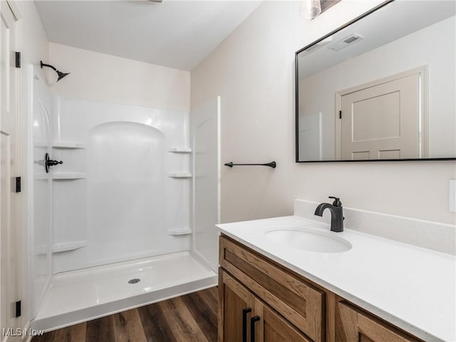 bathroom with a shower stall, visible vents, wood finished floors, and vanity