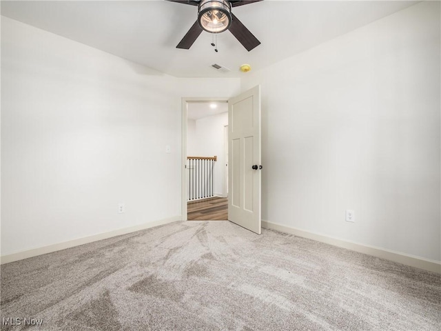 carpeted spare room featuring visible vents, baseboards, and ceiling fan