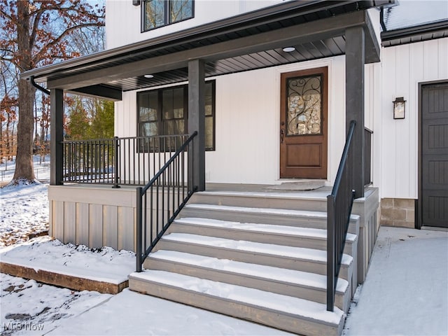 snow covered property entrance with a porch