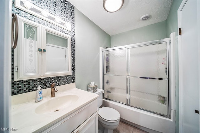 bathroom with backsplash, toilet, enclosed tub / shower combo, vanity, and a textured ceiling