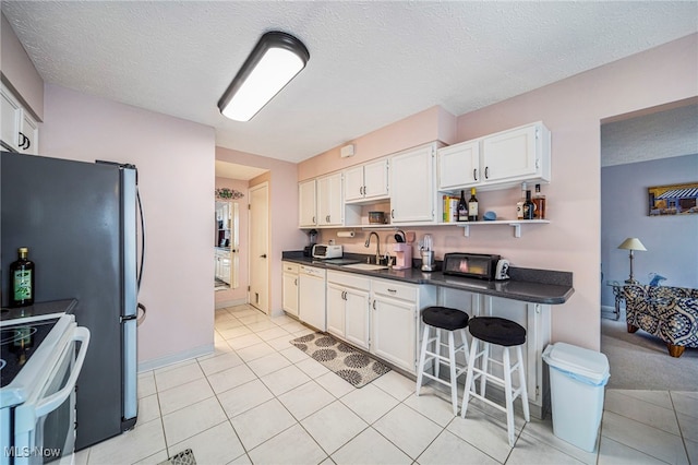 kitchen with white appliances, white cabinetry, a kitchen breakfast bar, open shelves, and dark countertops