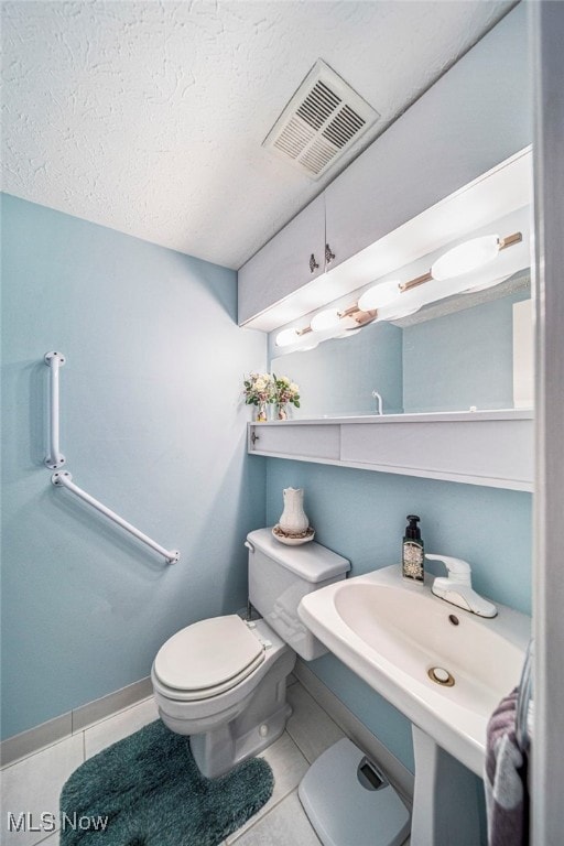 half bath with toilet, tile patterned flooring, visible vents, and baseboards