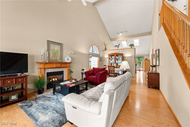 living area featuring a healthy amount of sunlight, light wood-style floors, baseboards, and high vaulted ceiling