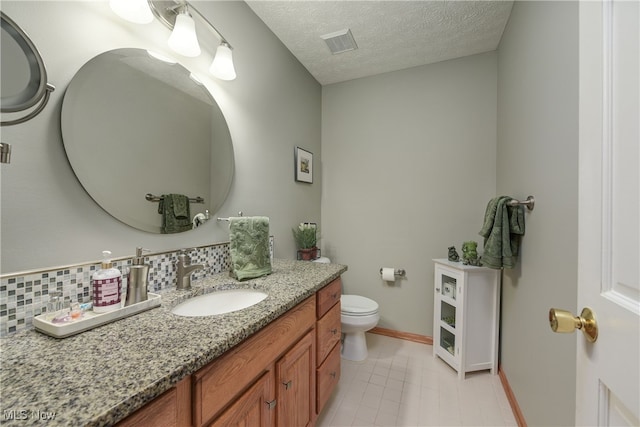 bathroom featuring visible vents, toilet, vanity, a textured ceiling, and baseboards