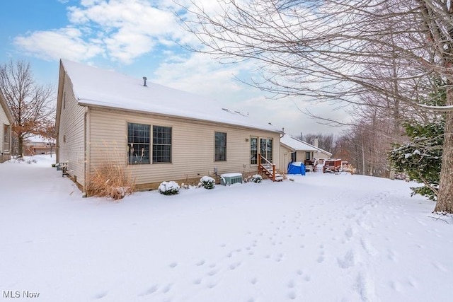 snow covered property with entry steps and central AC unit