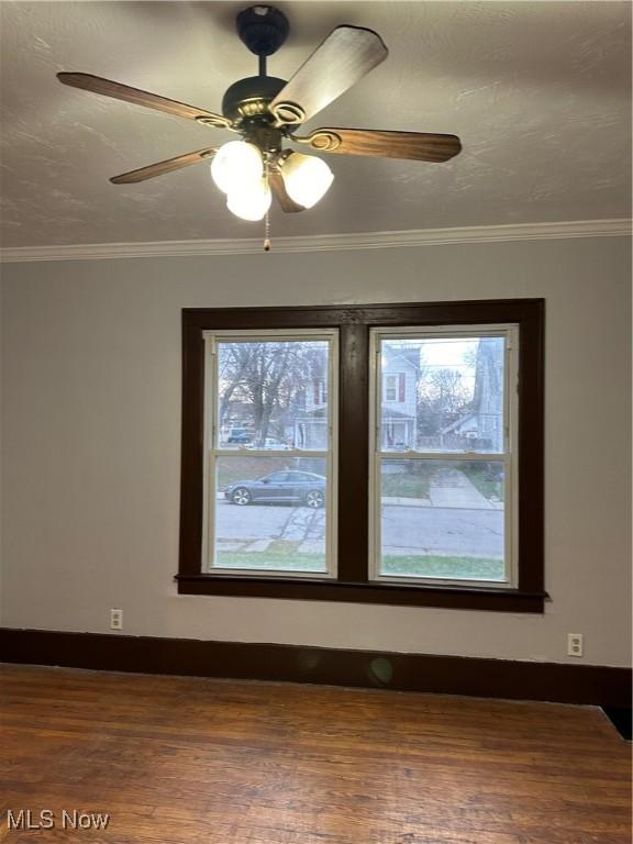 unfurnished room featuring baseboards, ornamental molding, and dark wood finished floors