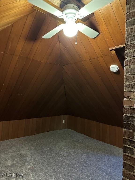 additional living space with ceiling fan and wooden walls