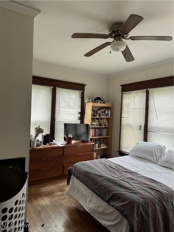bedroom with a ceiling fan, crown molding, and wood finished floors