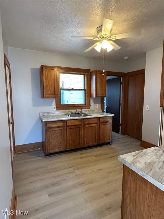 kitchen with brown cabinets, light wood finished floors, light countertops, and a sink