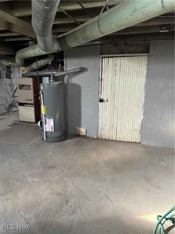 unfinished below grade area featuring concrete block wall and water heater