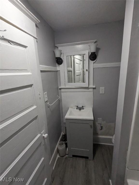 bathroom with toilet, baseboards, wood finished floors, and vanity