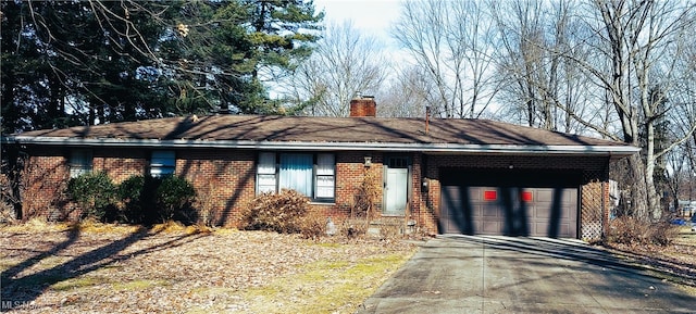 ranch-style home with concrete driveway, brick siding, a chimney, and an attached garage