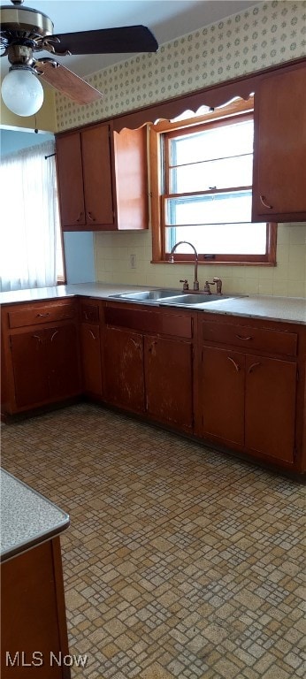 kitchen featuring light countertops, tasteful backsplash, a sink, and a ceiling fan