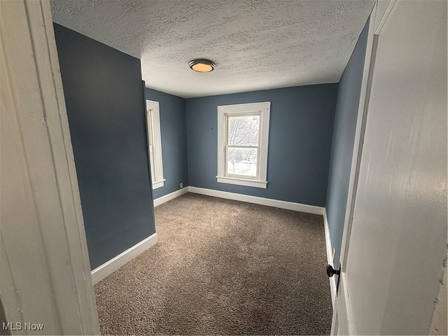 unfurnished room with a textured ceiling, carpet floors, and baseboards