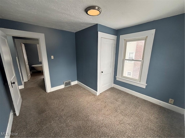 unfurnished bedroom featuring a textured ceiling, a closet, visible vents, and baseboards