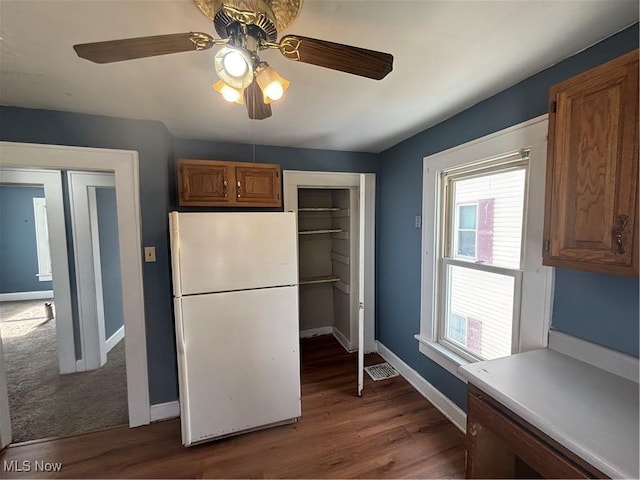 kitchen featuring brown cabinetry, freestanding refrigerator, and light countertops