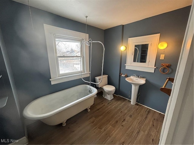 bathroom featuring a sink, a freestanding bath, toilet, and wood finished floors