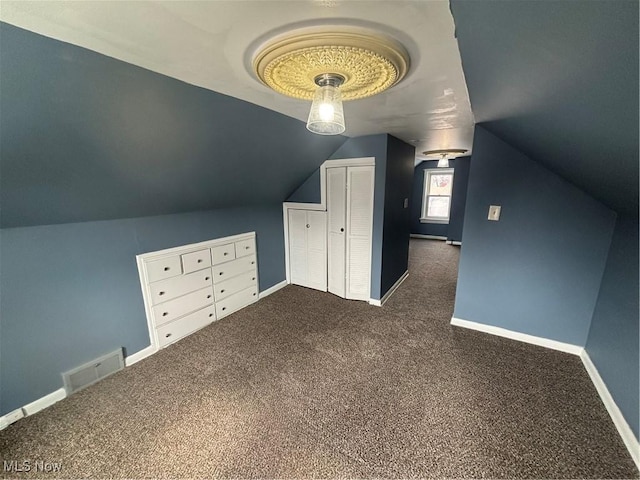 additional living space featuring baseboards, vaulted ceiling, visible vents, and dark carpet