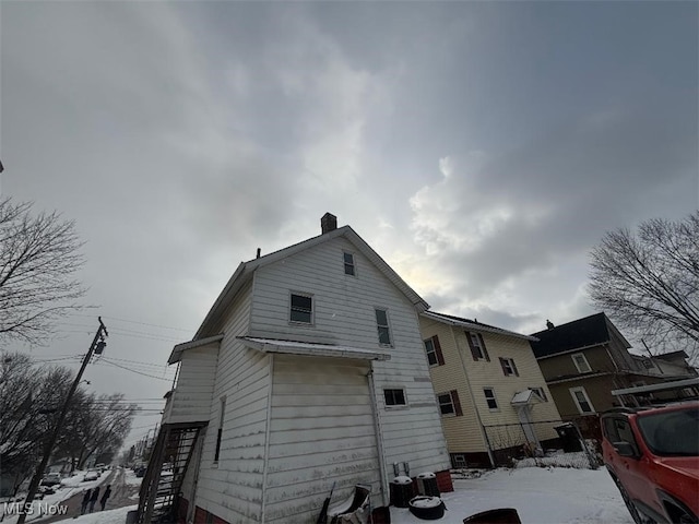 view of snow covered exterior with a chimney and stairway