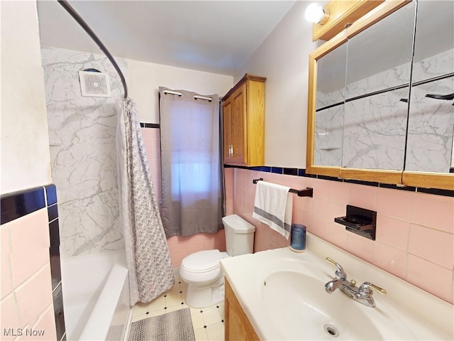 bathroom with toilet, shower / bath combo, tile walls, and vanity