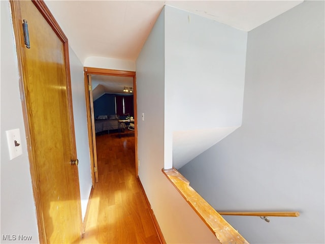 corridor featuring lofted ceiling, light wood finished floors, and an upstairs landing