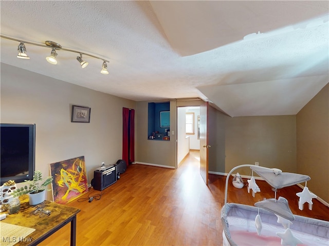 rec room featuring light wood-style floors, a textured ceiling, and baseboards