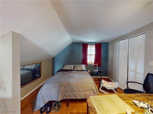 bedroom featuring lofted ceiling, wood finished floors, and baseboards