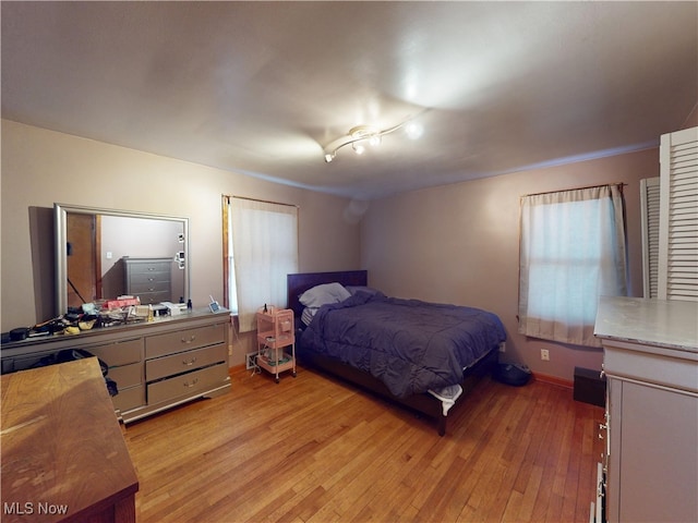 bedroom featuring light wood finished floors and baseboards