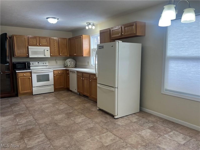 kitchen featuring white appliances, baseboards, hanging light fixtures, light countertops, and brown cabinets