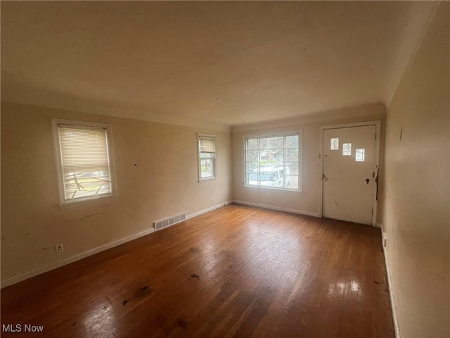 foyer with baseboards, visible vents, and wood finished floors