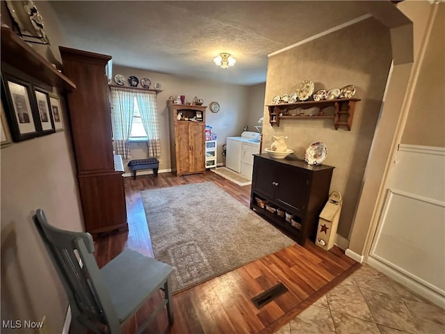 interior space featuring a textured ceiling, separate washer and dryer, wood finished floors, and baseboards