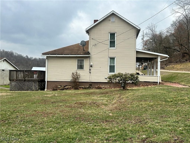 rear view of house featuring a deck and a yard