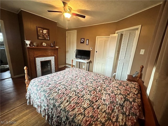 bedroom featuring a textured ceiling, crown molding, a fireplace, and wood finished floors