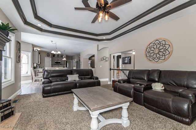 living room with arched walkways, a tray ceiling, ornamental molding, and baseboards