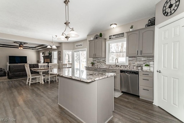 kitchen with a center island, pendant lighting, gray cabinets, stainless steel dishwasher, and open floor plan