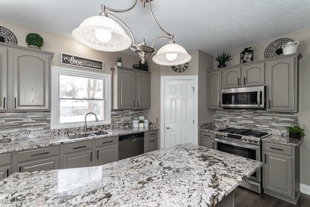 kitchen featuring appliances with stainless steel finishes, pendant lighting, a sink, and gray cabinets