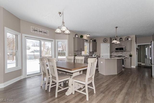 dining space featuring dark wood-type flooring and baseboards