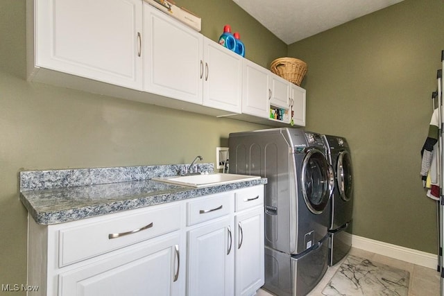 laundry area featuring independent washer and dryer, a sink, cabinet space, and baseboards