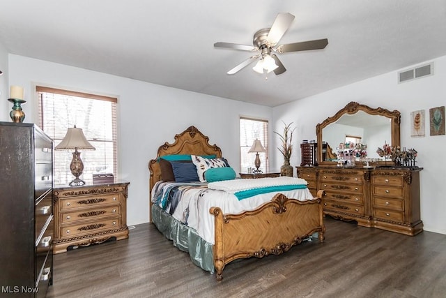 bedroom featuring a ceiling fan, visible vents, and dark wood finished floors